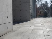 a concrete building with some windows next to some brick paving and stone ground with a bench in front