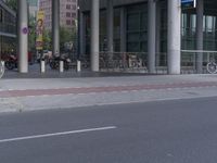 a man on a bike and some buildings and a city street with a bicycle rack