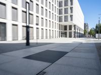 a concrete slab laying in the middle of a sidewalk surrounded by buildings and trees with the light on at the end of the street