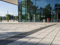 a man with a suitcase is looking at an empty walkway next to some glass buildings