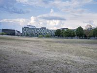 the landscape in front of some big buildings has a fenced off area with a lot of green