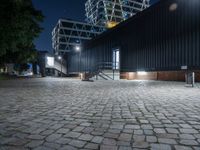 a black building sits across from another building with some stairs to it and is at night