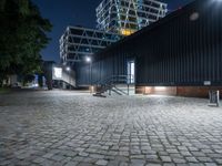 a black building sits across from another building with some stairs to it and is at night