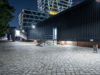 a black building sits across from another building with some stairs to it and is at night