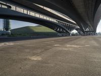 the road is empty with many cars parked on it near an overpass and a highway bridge