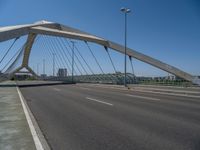 a truck driving across a bridge near a street corner near buildings and a bridge with many cables