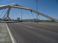 a truck driving across a bridge near a street corner near buildings and a bridge with many cables