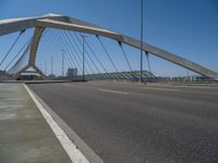 a truck driving across a bridge near a street corner near buildings and a bridge with many cables