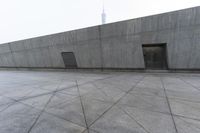 a large gray building with some concrete walls and a closed door in it's center