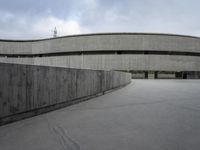 a building with cement roof near green grass and lawn in front of it, under a gray sky