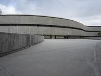 a building with cement roof near green grass and lawn in front of it, under a gray sky