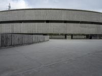 a building with cement roof near green grass and lawn in front of it, under a gray sky