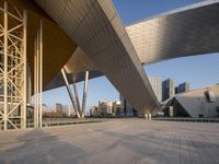 modern building architecture with a blue sky and a few buildings in the background under a bridge