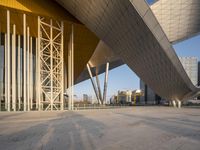 modern building architecture with a blue sky and a few buildings in the background under a bridge