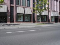 a building with awnings and some trees in front of it and a street