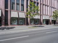 a building with awnings and some trees in front of it and a street