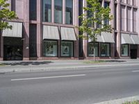 a building with awnings and some trees in front of it and a street