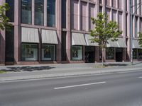 a building with awnings and some trees in front of it and a street