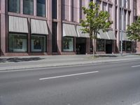 a building with awnings and some trees in front of it and a street