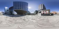 a panorama fisheye view of a large building, with several curved objects on the ground