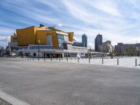 a large yellow building in a city near a body of water with tall buildings on either side