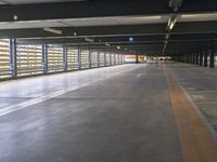 the inside walkway of an empty building with the doors open and the parking spaces empty