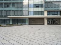 a large gray building with a small courtyard in front of it has a sky background