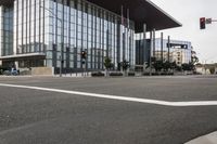 an intersection near a large modern building with many windows and a crosswalk at it