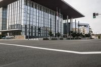 an intersection near a large modern building with many windows and a crosswalk at it