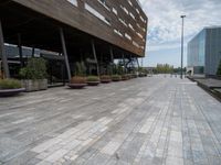 the empty walkway leads to a modern building in this city area of a large, narrow, stone area