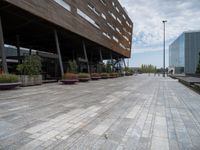 the empty walkway leads to a modern building in this city area of a large, narrow, stone area