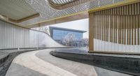 a photo of the exterior of a building with curved ramps to sit alongside it on a tile floor