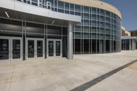 a modern building with glass walls and double doors to the front of the building on either side of a path