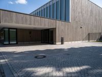 the entrance of this modern building has a brick walkway and doord parking area below