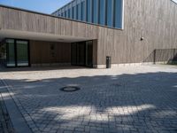 the entrance of this modern building has a brick walkway and doord parking area below