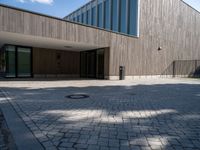 the entrance of this modern building has a brick walkway and doord parking area below