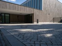 the entrance of this modern building has a brick walkway and doord parking area below