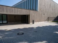 the entrance of this modern building has a brick walkway and doord parking area below