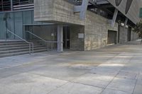 there is a concrete sidewalk in front of the entrance of a building with steps leading up to it
