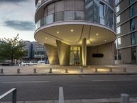 an entrance to a modern building in a city by a sidewalk with columns and parking spaces