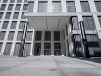 the side of a modern building with glass windows and some poles on either side of the room