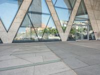 the sidewalk outside a modern building with geometric designs on it's sides and windows