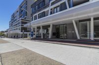 the empty street outside a modern building with glass windows on it's sides and a blue sky above