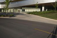 this is a modern building with glass and wood accents and glass walls, along the street, a lawn and a tree