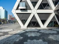 the modern building is constructed into hexagons on a sidewalk of brick stones