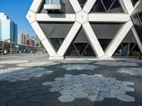 the modern building is constructed into hexagons on a sidewalk of brick stones