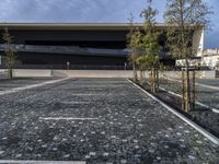 a modern building that stands out in the street with brick paving on the front of the building