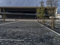 a modern building that stands out in the street with brick paving on the front of the building