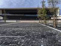 a modern building that stands out in the street with brick paving on the front of the building