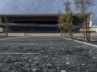 a modern building that stands out in the street with brick paving on the front of the building